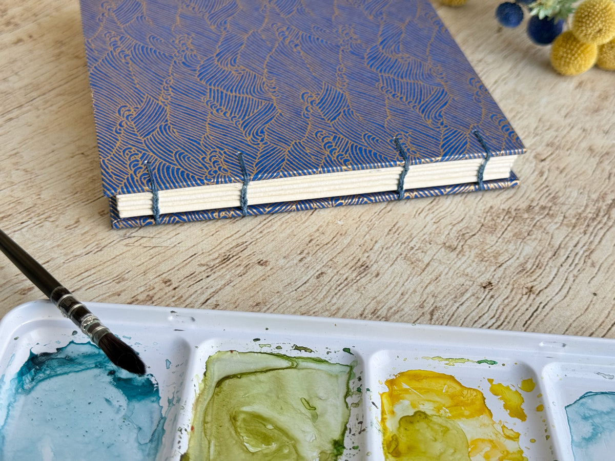 Carnet d'aquarelle découverte fait main avec sa couverture en papier japonais motif océan bleu nuit, reliure copte sur la tranche
