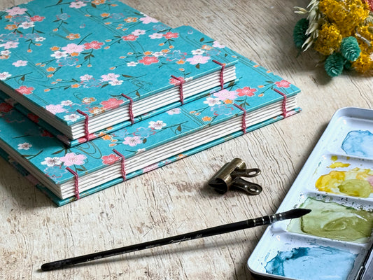 carnets d'aquarelle fait main, reliure copte visible sur la tranche des carnets