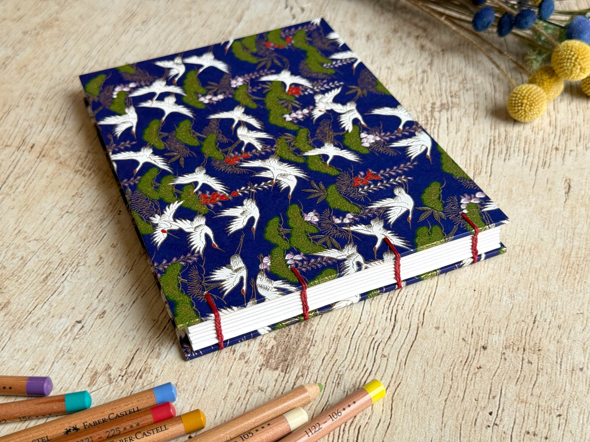 Détail du papier de croquis et de la reliure cousue main couverture Grues pins glycines sur fond bleu